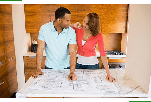 A man and woman looking at plans on top of a table.